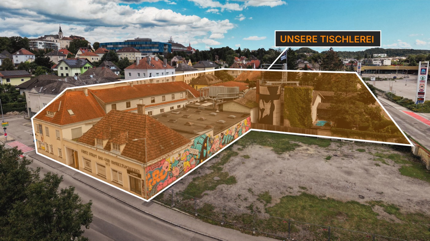 Luftaufnahme des Quartiers Unsere Tischlerei in Melk — das Gelände mit der bunten Mural-Fassade ist weiß umrandet, im Hintergrund der Ort Melk.